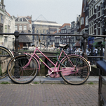 852091 Afbeelding van een roze fiets tegen de balustrade van de Maartensbrug over de Oudegracht te Utrecht, met op de ...